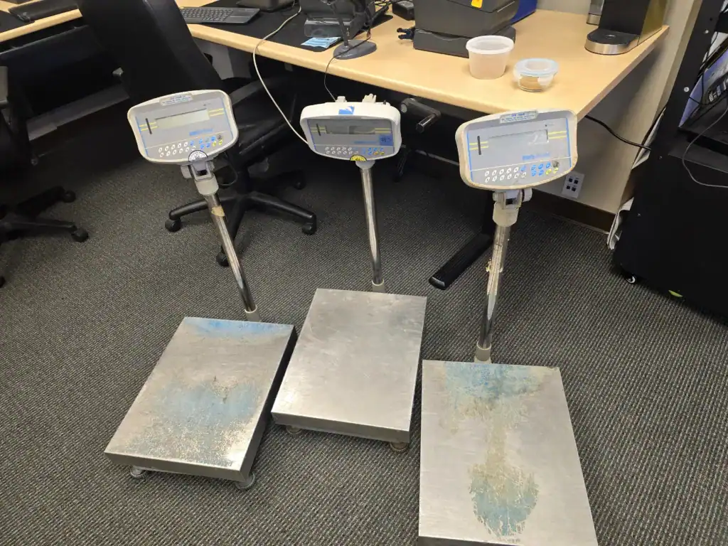 Three Adam platform scales after harvest, with print buttons caked in cannabis resin and worn weighing platforms